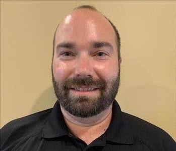 Male SERVPRO employee with green eyes, dark hair, and beard smiling